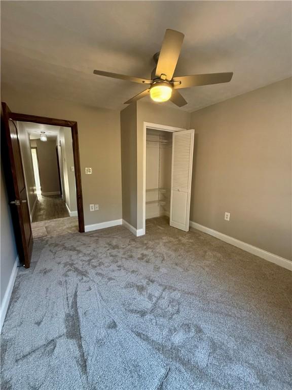 unfurnished bedroom with ceiling fan, a closet, and carpet floors