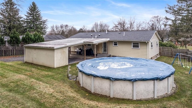 rear view of house featuring a yard, a playground, and a covered pool