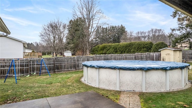 view of swimming pool with a yard, a playground, and a storage shed