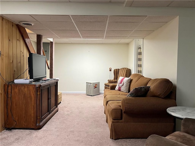 living room with a paneled ceiling, light carpet, and wooden walls