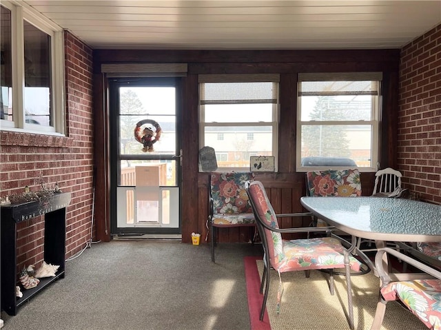 dining space with carpet floors, a brick fireplace, and brick wall