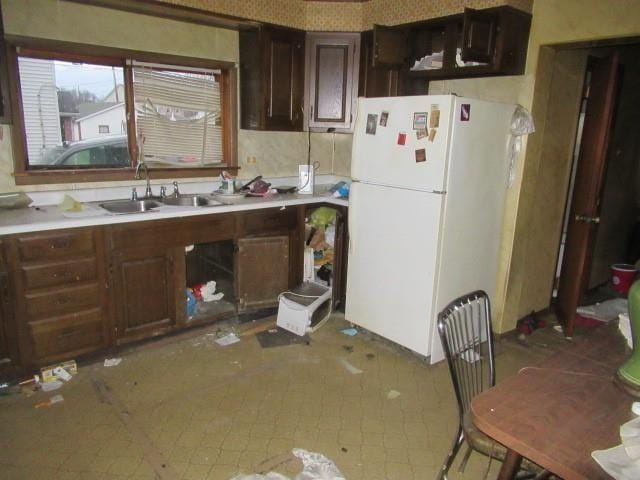 kitchen with white fridge, dark brown cabinetry, and sink