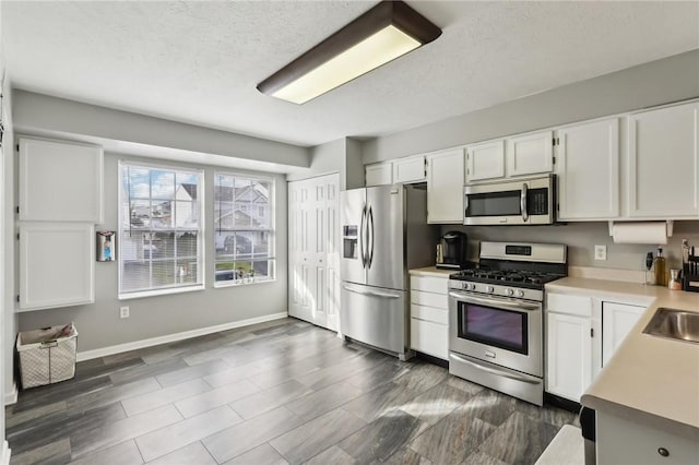 kitchen featuring sink, white cabinetry, a textured ceiling, and appliances with stainless steel finishes