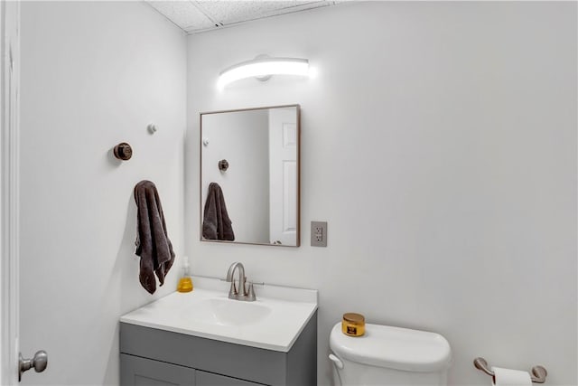 bathroom with a paneled ceiling, vanity, and toilet