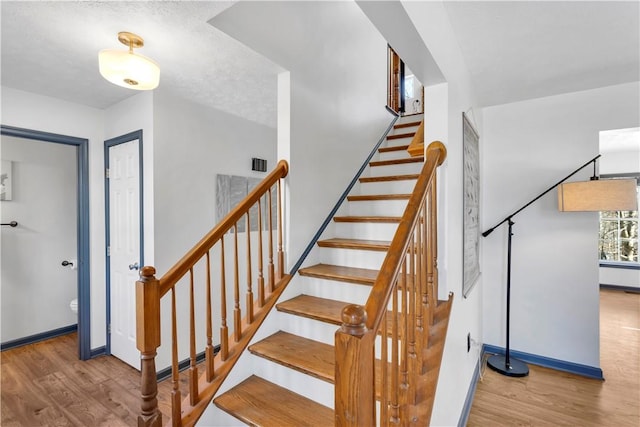 stairway featuring a textured ceiling and hardwood / wood-style flooring