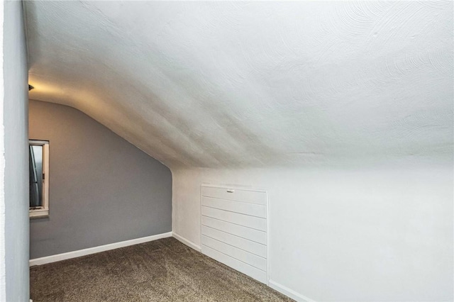 bonus room featuring dark carpet, a textured ceiling, and vaulted ceiling