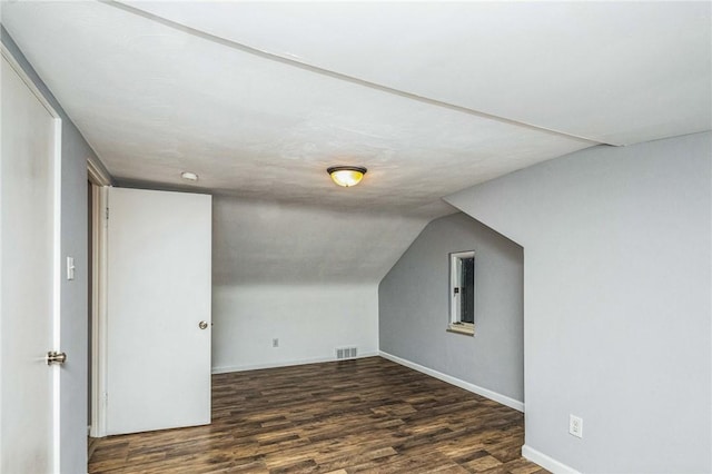 additional living space with dark wood-type flooring and vaulted ceiling