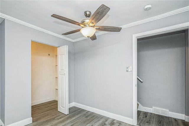 unfurnished bedroom featuring a closet, ceiling fan, hardwood / wood-style floors, and crown molding