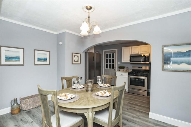 dining area with hardwood / wood-style flooring, an inviting chandelier, and crown molding