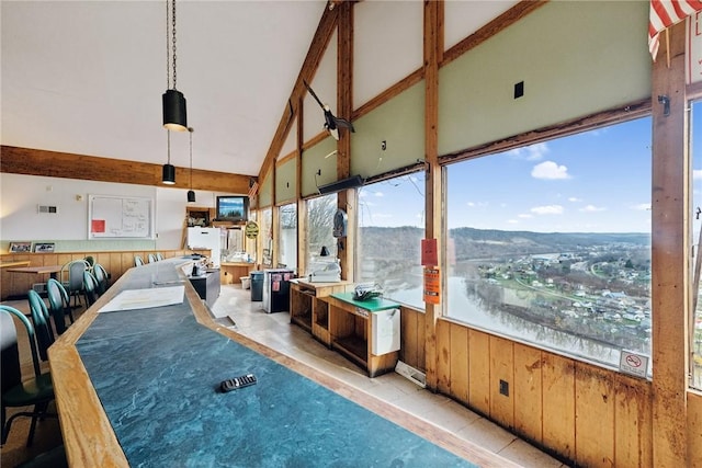 rec room with wood walls, light tile patterned floors, and high vaulted ceiling