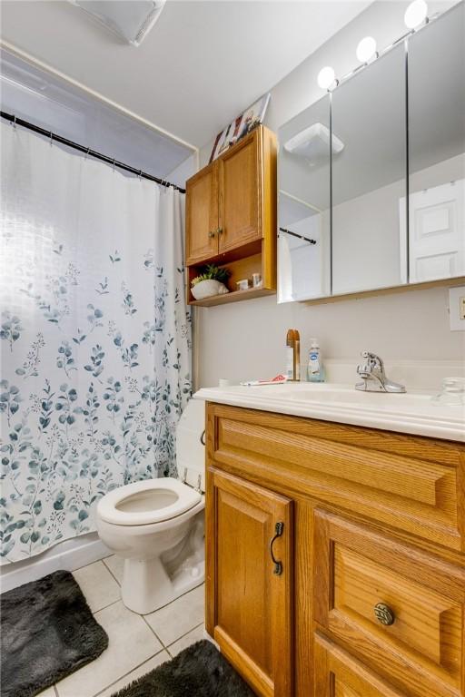 bathroom with tile patterned flooring, vanity, toilet, and curtained shower