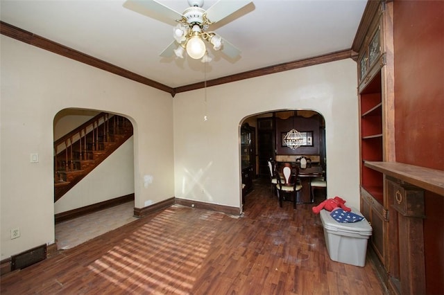 empty room with ceiling fan with notable chandelier, dark hardwood / wood-style flooring, and crown molding