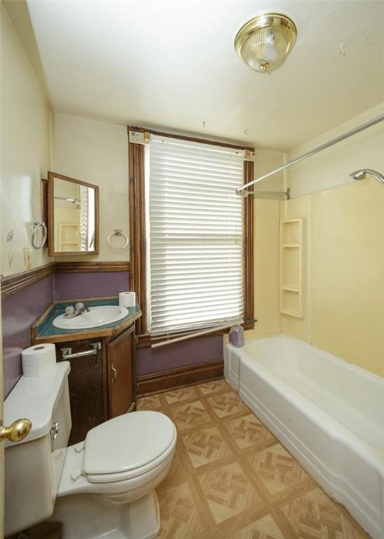 full bathroom featuring parquet floors, toilet, vanity, and washtub / shower combination