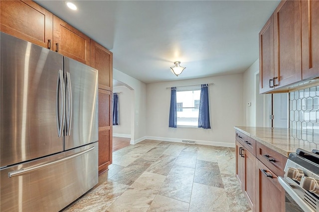 kitchen with light stone counters, stainless steel appliances, and tasteful backsplash