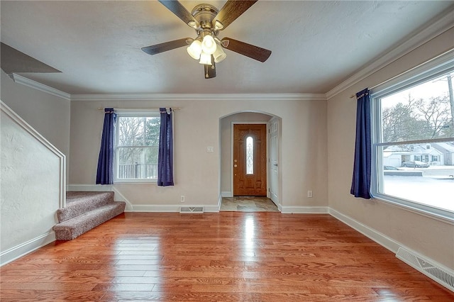 foyer entrance with ceiling fan, crown molding, a wealth of natural light, and light hardwood / wood-style flooring