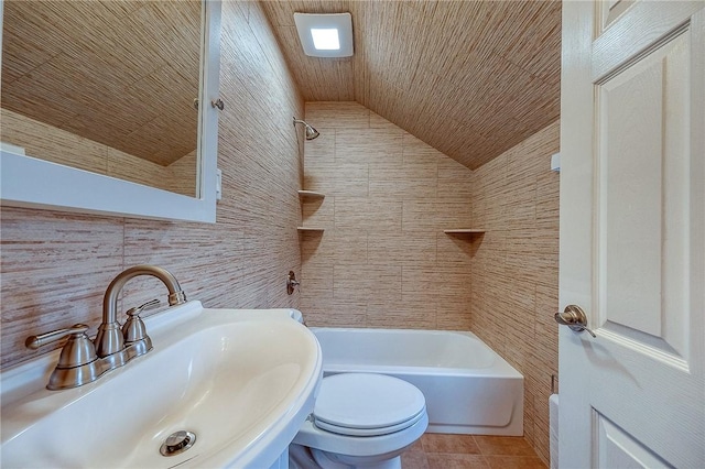 full bathroom with tile patterned floors, sink, vaulted ceiling, toilet, and tile walls