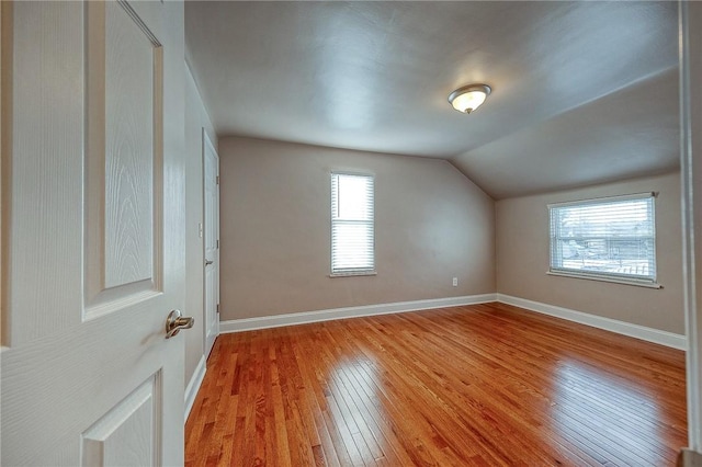 additional living space with a healthy amount of sunlight, lofted ceiling, and light wood-type flooring