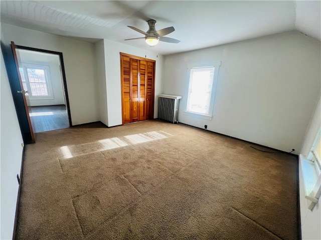 unfurnished bedroom with radiator heating unit, light carpet, a closet, ceiling fan, and lofted ceiling