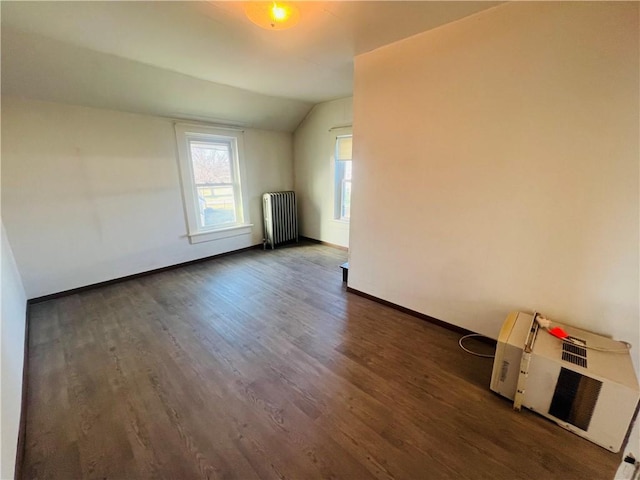 spare room featuring radiator heating unit, dark wood-type flooring, and vaulted ceiling