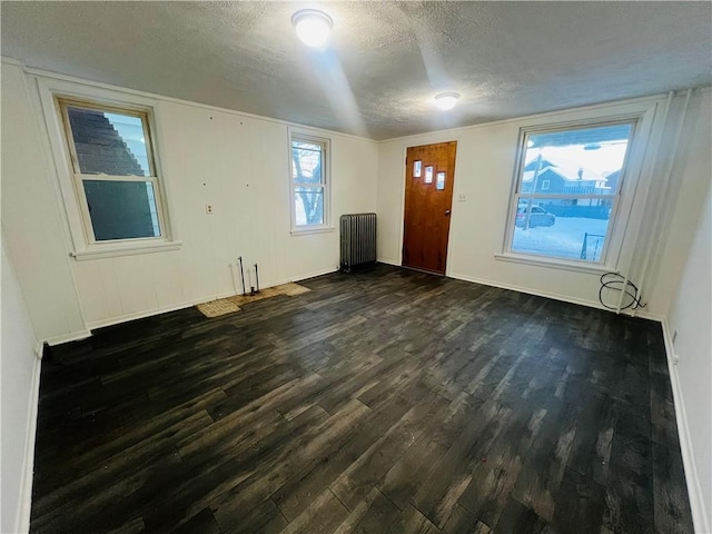 foyer entrance featuring radiator, dark wood-type flooring, and a textured ceiling