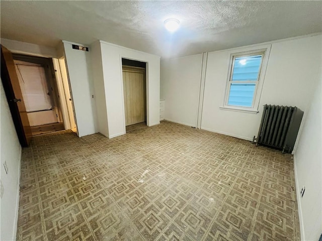 unfurnished bedroom featuring a textured ceiling and radiator heating unit