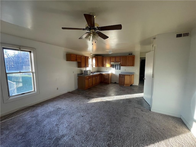 kitchen featuring ceiling fan and dark carpet