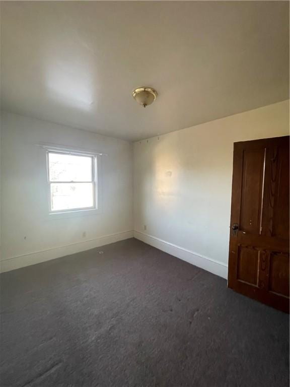 unfurnished room with dark carpet