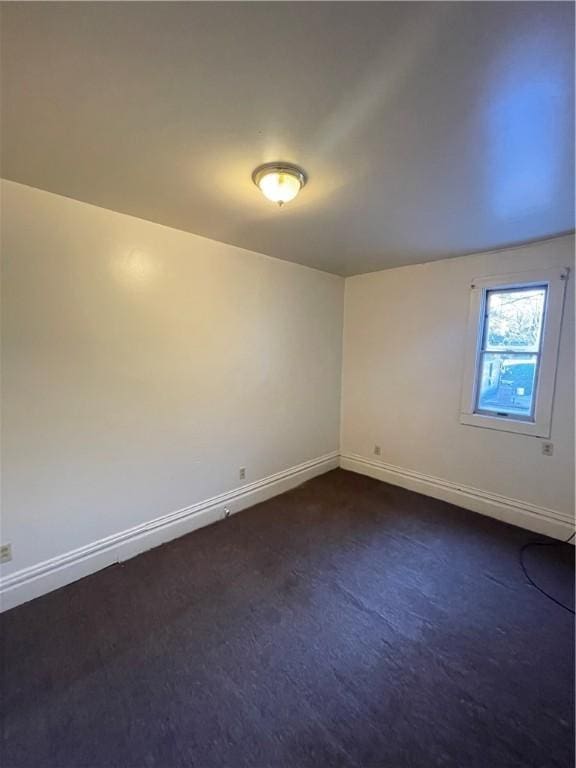 spare room featuring dark colored carpet