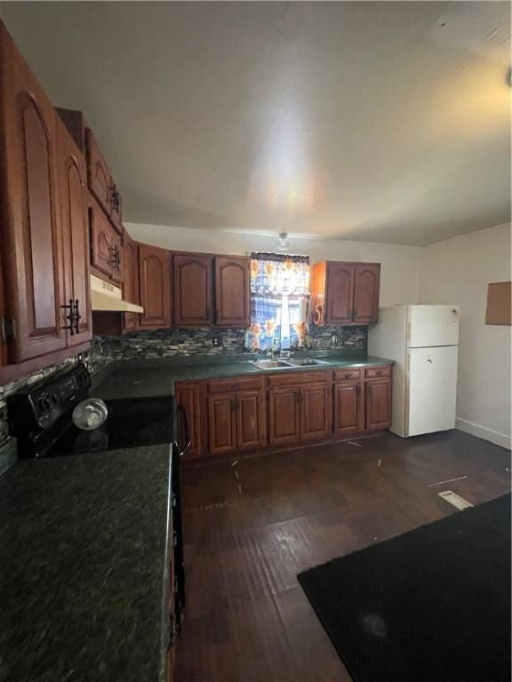 kitchen featuring decorative backsplash, dark wood-type flooring, sink, white refrigerator, and black range