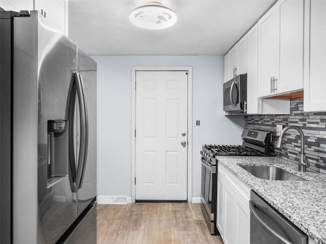 kitchen featuring white cabinetry, sink, light stone countertops, and appliances with stainless steel finishes