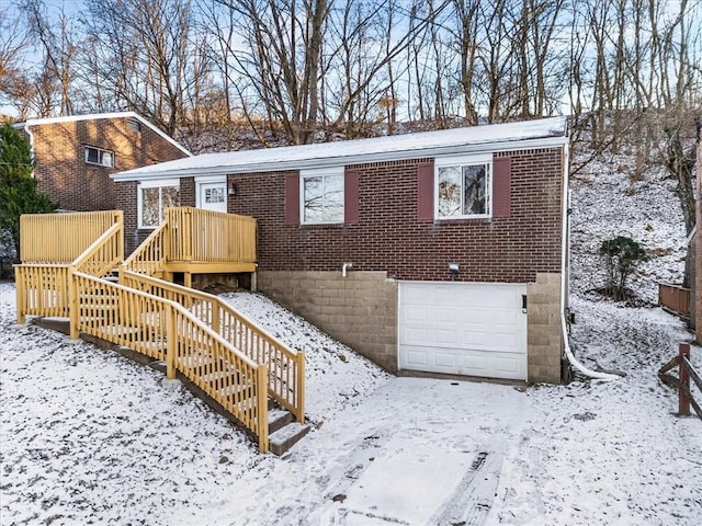 snow covered rear of property featuring a garage