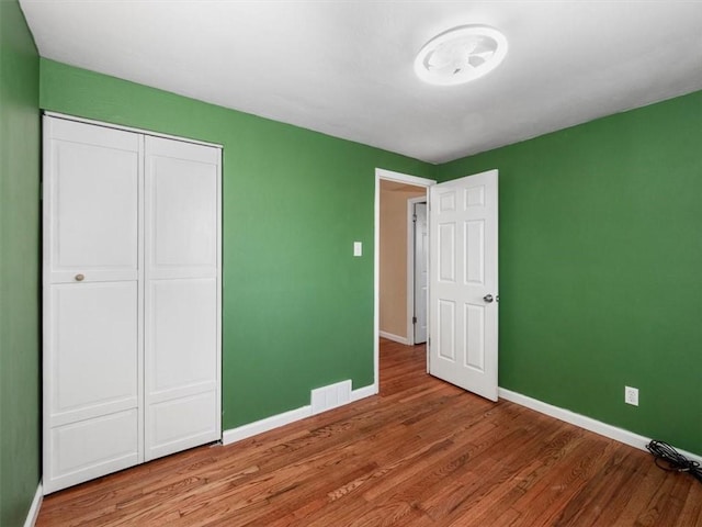 unfurnished bedroom with hardwood / wood-style flooring and a closet