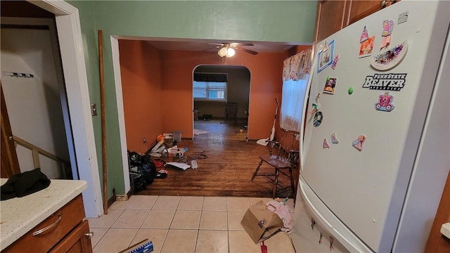 interior space with ceiling fan, white fridge, light stone countertops, and light wood-type flooring