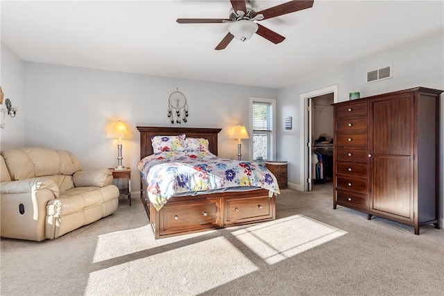 carpeted bedroom with a walk in closet, a closet, and ceiling fan