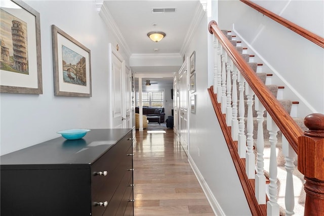 corridor with light hardwood / wood-style floors and crown molding