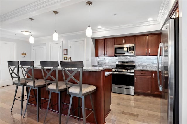 kitchen with light stone countertops, pendant lighting, a kitchen island, and stainless steel appliances