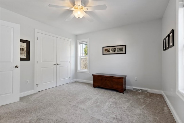 unfurnished bedroom with ceiling fan, a closet, and light colored carpet