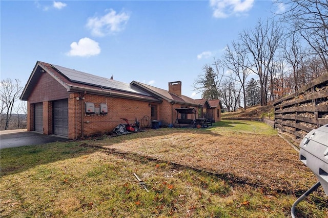 view of side of home with solar panels, a garage, and a lawn