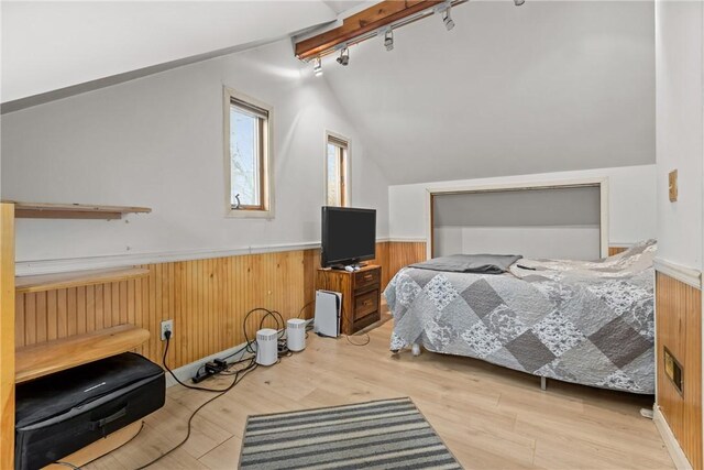 bedroom featuring vaulted ceiling, wooden walls, and light hardwood / wood-style floors