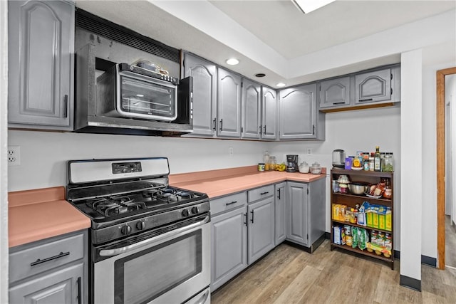 kitchen featuring stainless steel appliances, gray cabinetry, and light wood-type flooring