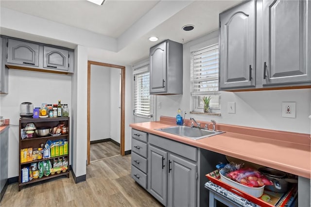 kitchen with gray cabinets, sink, and light wood-type flooring