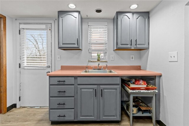 kitchen with light wood-type flooring, plenty of natural light, sink, and gray cabinetry