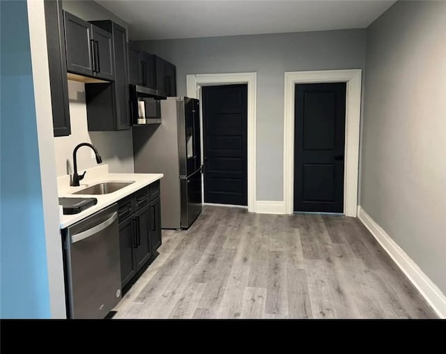 kitchen with sink, appliances with stainless steel finishes, and light hardwood / wood-style flooring