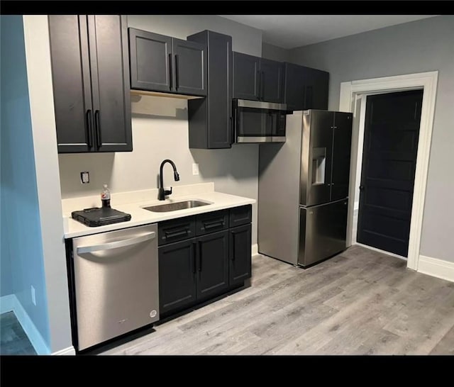 kitchen featuring light wood-type flooring, stainless steel appliances, and sink