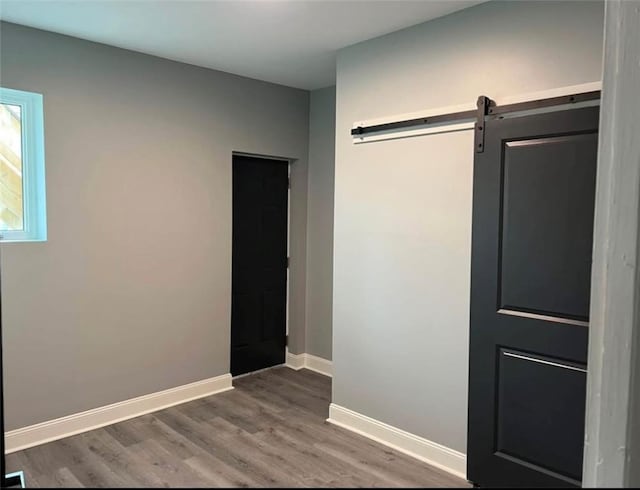 unfurnished room with hardwood / wood-style floors and a barn door