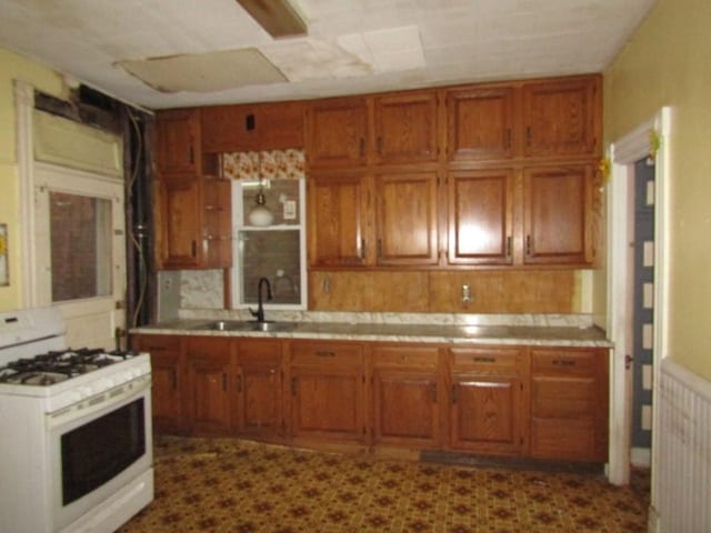 kitchen featuring sink, white gas range oven, and tasteful backsplash