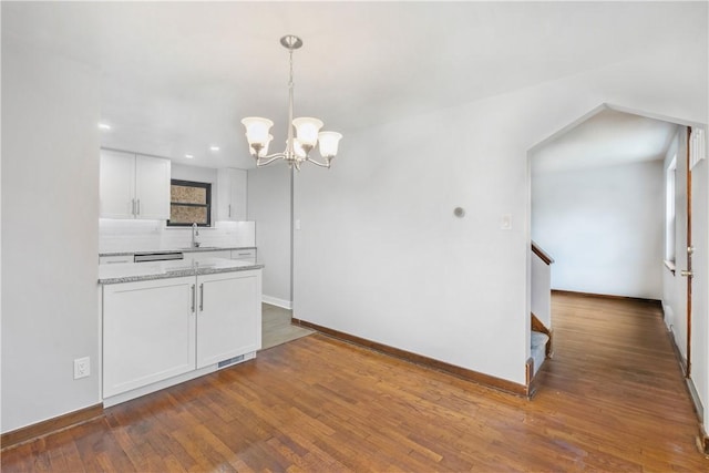 kitchen with white cabinets, light stone counters, dark wood-type flooring, and hanging light fixtures