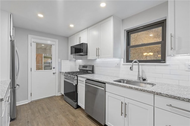 kitchen featuring white cabinets, sink, light stone countertops, and stainless steel appliances