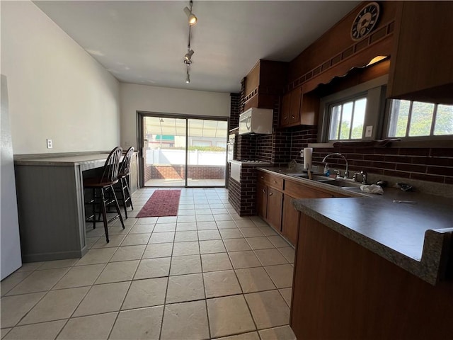 kitchen with a healthy amount of sunlight, a kitchen bar, sink, and light tile patterned flooring