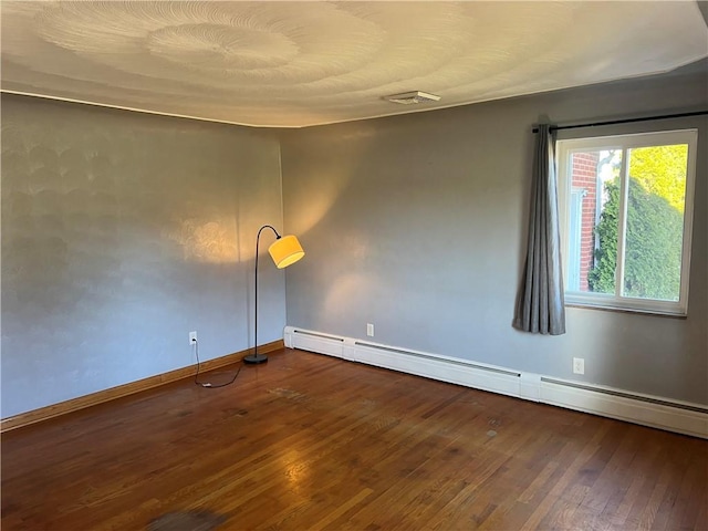 spare room with dark hardwood / wood-style flooring and baseboard heating